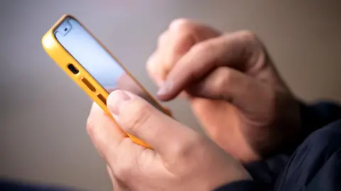 Getty Images A close-up picture of a man using a smartphone. 