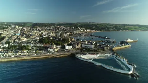 BBC An aerial view of Penzance, Cornwall, on a sunny day - showing the town, the coastline, and Jubilee Pool