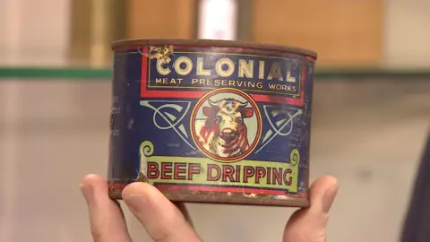 A close-up of the blue Colonial Beef Dripping can. There's a drawing of a cow at the centre. 