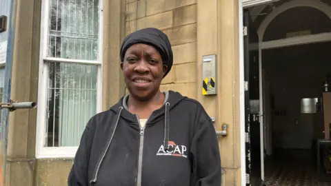 A woman smiling wearing an African Caribbean Achievement Project jumper