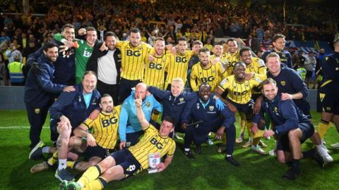The players and coaching staff of Oxford United pose for a photo at full-time following the team's victory in the League One play-off semi-final against Peterborough United