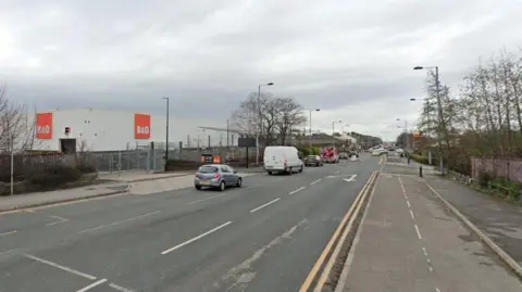 The image shows the road running along retail stores and fast food restaurants.