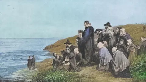 Getty Images An old-fashioned illustration shows a group of early settlers kneeling and standing on a grassy shoreline, looking out across the sea.