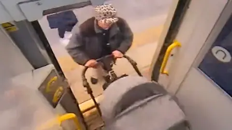 CLEVELAND POLICE A person wearing a leopard print hat pushes a pushchair onto a train