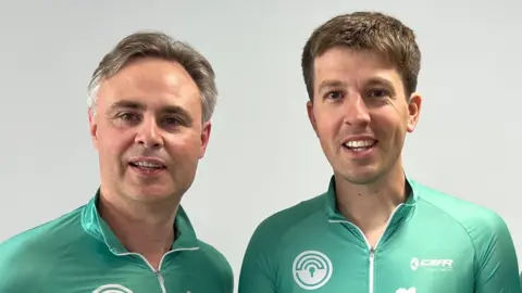 Two men, smiling. They are wearing matching mint green cyclist tops.
