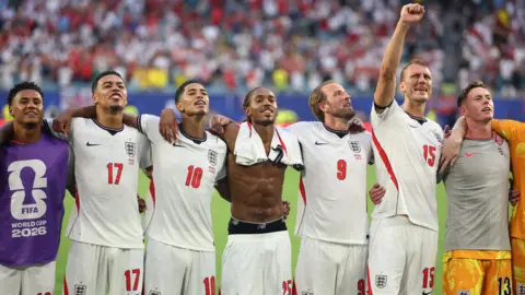 Reuters The England team in full kit, smiling and standing with their arms around each other on the pitch after the Norway game. 