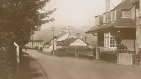 The Oakbank Inn A black and white picture of the main street in Sandbank. There are more buildings in this picture than above and the hotel is far off in the distance. 