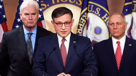 EPA Mike Johnson wears a blue suit with a stern expression standing at a podium