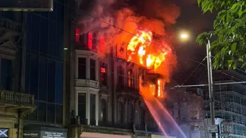 Dillon Laing An old Victorian building on fire with jets of water directed at the flames