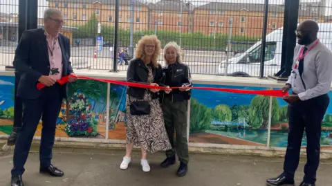Network Rail Aimi Rix cuts the ribbon to unveil the artwork display