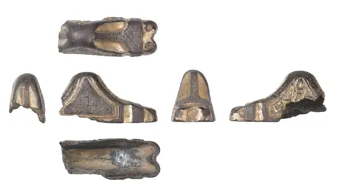Colchester and Ipswich Museum Service Six views of a near-complete silver gilt sword pommel cap, dating to about AD500 to 600. From above it is a rectangle and from the side it is a low pyramid in shape. It in made from blackened silver and the gilt stands out in a a dull gold colour.