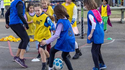 Children in Twickenham playing football at school