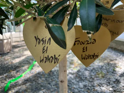 A tree with heart shaped golden leaves attached with the names of the El Wahabi on them