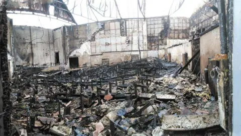 Paul Starck Charred remains of the cinema auditorium. The roof has collapsed and the floor is covered in charred debris