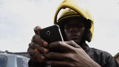 AFP MaxOkada rider decks out in bibs and helmet in company colours as he checks Apps information, on September 4, 2019