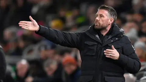 Rob Edwards gesturing towards his players on the pitch while manager of Luton