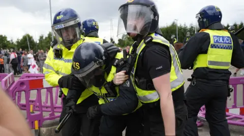 PA Two officers carry a colleague away from the scene.