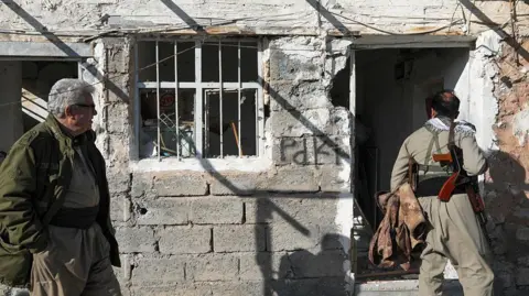 Getty Images Men inspect damage to the Azadi Camp of the Kurdistan Democratic Party of Iran