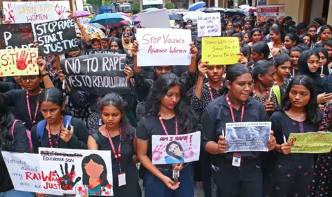 Arun Chandra Bose/BBC Un gran grupo de mujeres vestidas con camisetas negras sostiene carteles durante una protesta contra la violencia contra las mujeres.