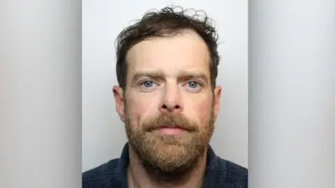 Wiltshire Police A man with a beard and blue jumper looking at the camera.