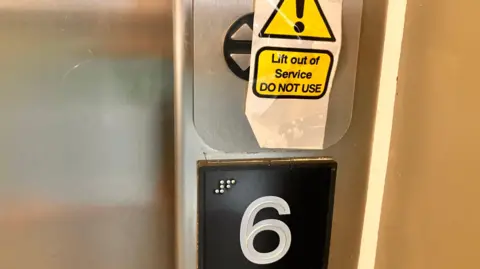 A lift button covered with a sign that reads: Lift out of service. Do not use.