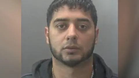 Cambridgeshire Constabulary A custody image of a man wearing a grey hoodie.