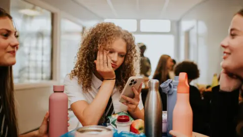 Girl had head in one hand and phone in the other looking bored