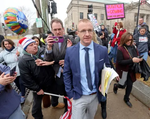 Getty Images Aidan Kearney walks away from court with papers in his hands as a crowd follows him