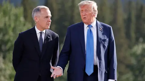 Canadian Prime Minister Mark Carney and US President Donald Trump both wearing navy blue suits talking together at the G7 meeting in June 