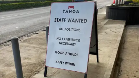 Sign the hotel reading “All positions, no experience required, good attitude, work inside” 