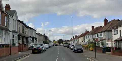 Google A residential street with cars and terraced houses along either side.