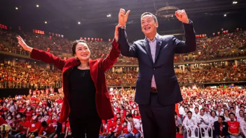 Getty Images Paetongtarn Shinawatra and Srettha Thavisin, Prime Ministerial candidates for Thailand's Pheu Thai party, greet supporters during an election rally on May 12, 2023 in Bangkok.