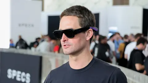 Getty Images Head and shoulders photo of a man wearing chunky black sunglasses and a black t-shirt