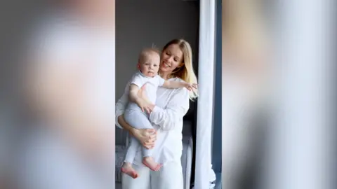 A woman smiles at her baby as she holds them