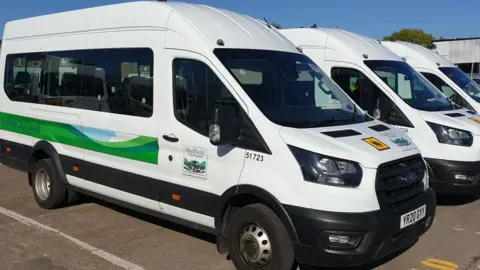 Sheffield City Council White minibuses parked side by side bearing a Sheffield City Council logo