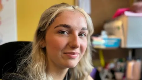 Mabli Cunnah-McMillan, 18, who has finished her apprenticeship at Mazuma smiles at the camera in an office