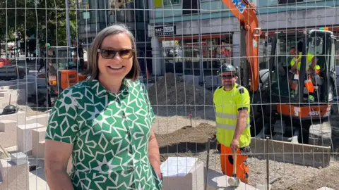 Nottingham City Council A councillor and a worker, both in shades, smiling either side of a construction site fence