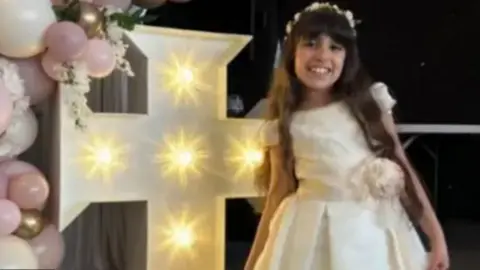 Family handout Alice da Silva Aguiar smiles at the camera while wearing her white Communion dress.