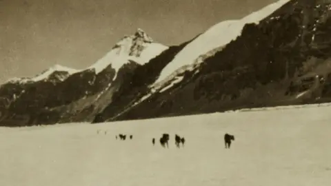 Courtesy Sotheby’s Photograph of mountaineers crossing a glacier, with Mount Everest in the background. The black and white image shows several Himalayan peaks.