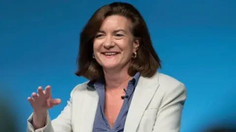 Eluned Morgan smiling during a speech at Welsh Labour conference in front of a lectern.