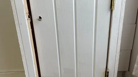 A white fire safety cupboard with a door that does not close