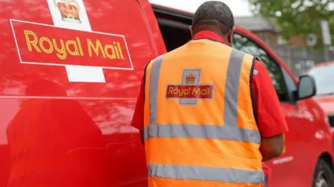 Getty Images Postal worker stands next to a Royal Mail branded van