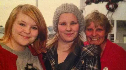 Jordan Findlay A group of three women in a smiling, happy family photo. They are a middle aged mum and her two teenage daughters.