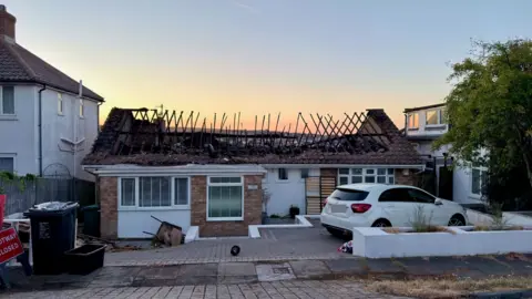 Eddie Mitchell A bungalow with a burnt roof at sunrise. 
