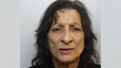 Avon and Somerset Police Rosa Kovacs in a police mugshot. She has dark brown hair and prominent cheek bone area with a ruffled brow. Her hair is wavy and she is looking at the camera with dark brown eyes.