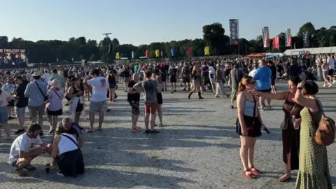 People are seen standing around in a large crowd