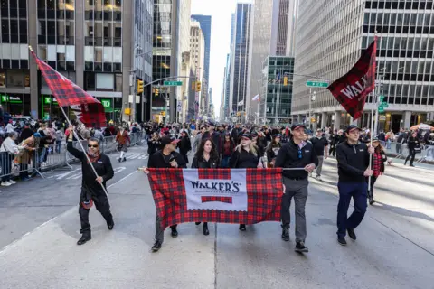 PA Media Marchers holding a red tartan Walker's Shortbread banner