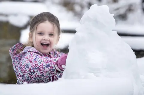 PA Media Three-year-old Molly plays in the snow