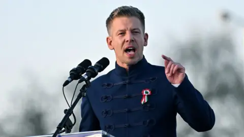 EPA A man with cropped hair and a fancy blue jacket stands at a microphone