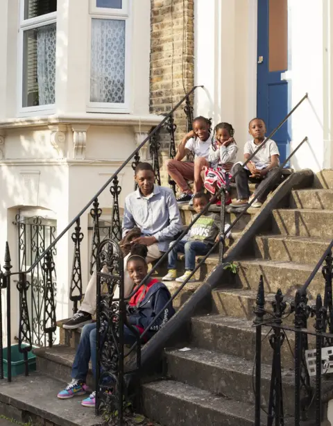 Jorn Tomter A group of children sit outside their house